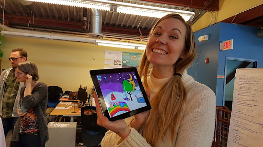 A woman holds up an ipad screen showing Starfishers being played