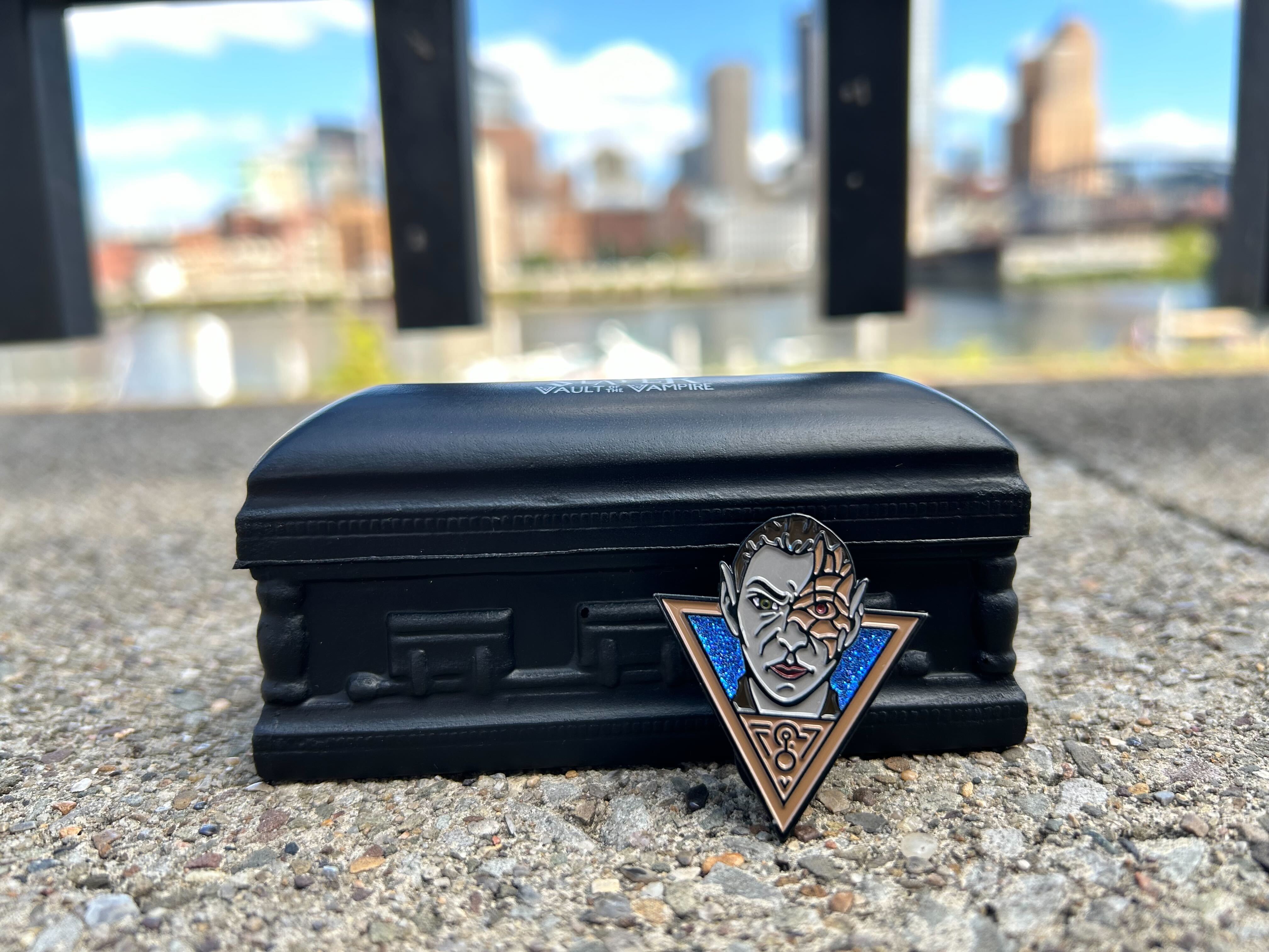 Silent Slayer promo items of a sparkling vampire pin and coffin-shaped stress reliever with Pittsburgh in the background.